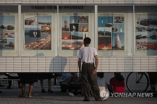 A Pyongyang citizen looks at posters of missile launches on July 25, 2017. (AFP-Yonhap)