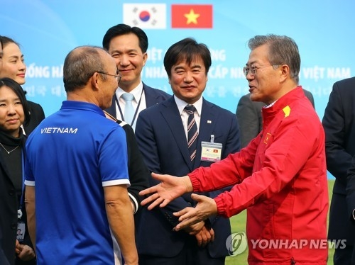 South Korean President Moon Jae-in (R) speaks with Park Hang-seo, South Korean coach of Vietnam's national football team, during his visit to the Vietnam Football Federation in Hanoi on March 22, 2018. (Yonhap)