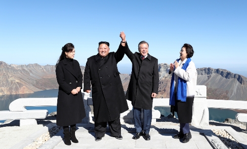 South Korean President Moon Jae-in (second from R) and North Korean leader Kim Jong-un (second from L) hold up their hands after reaching Changgun-bong, the peak of Mount Paekdu, during their one-day trip to the tallest mountain in North Korea on Sept. 20, 2018, one day after their bilateral summit in Pyongyang. The trip also involved Kim's wife, Ri Sol-ju (L) and Moon's wife, Kim Jung-sook (R). (Joint Press Corps-Yonhap)