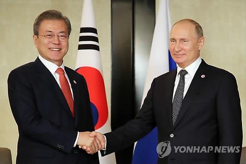 South Korean President Moon Jae-in (L) shakes hands with his Russian counterpart, Vladimir Putin, at a meeting in Singapore on Nov. 14, 2018. (Yonhap)