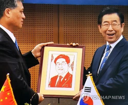 Seoul Mayor Park Won-soon (R) poses with a gift of a portrait from Ma Xingrui, governor of the southern Chinese province of Guangdong, at his office in downtown Seoul on April 5, 2019. The Chinese governor mistakenly gave the mayor a portrait of Gyeonggi Province Gov. Lee Jae-myung. (Yonhap)