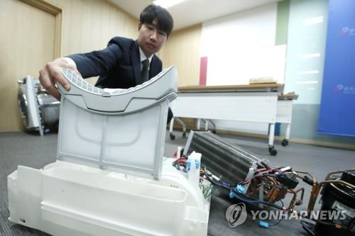 An employee at the Korea Consumer Agency shows a condenser, a key part of a clothes dryer made by LG Electronics Inc., at its office in Seoul in this file photo taken on Aug. 29, 2019. (Yonhap)