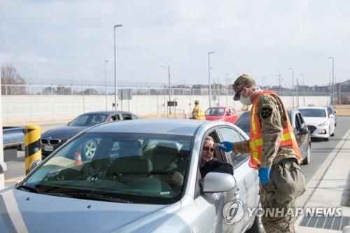 A military guard at U.S. Army Garrison Humphreys in Pyeongtaek, 70 kilometers south of Seoul, checks the temperature of a driver to screen entrants to the compound for the novel coronavirus on Feb. 28, 2020, in the photo provided by United States Forces Korea. (PHOTO NOT FOR SALE) (Yonhap)