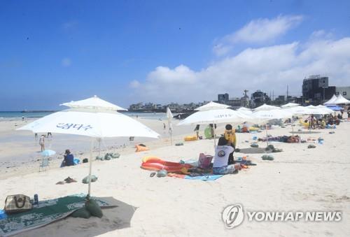 Vacationers keep a distance from one another at Hyeopjae Beach of Jeju Island on its opening day, July 1, 2020. (Yonhap)