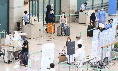 This photo taken July 28, 2020, shows health workers guiding arrivals at Incheon International Airport, west of Seoul. (Yonhap)