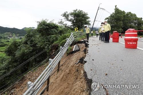 Officials inspect a road partially swept away by torrential rain in Namwon, North Jeolla Province, on Aug. 10, 2020, in this photo provided by the Ministry of Land, Infrastructure and Transport. (PHOTO NOT FOR SALE) (Yonhap)