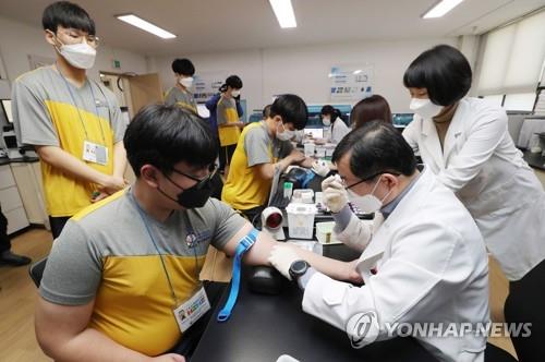 Aspiring soldiers wearing masks have their blood taken during a medical checkup at the Seoul office of the Military Manpower Administration on Feb. 3, 2020, part of the year's first batch of applicants evaluated by the office. All able-bodied South Korean males are required to serve roughly two years in the military. (Yonhap)