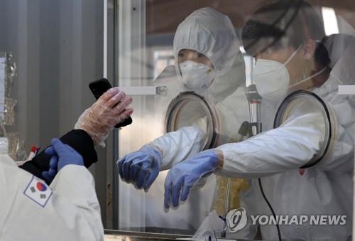 In this file photo taken on Jan. 19, 2021, a foreign national (R) reads a translation of a Korean message on coronavirus tests at a temporary testing station in central Seoul. (Yonhap)