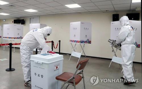 This file photo taken on April 1, 2021, shows quarantine officials disinfecting a polling station in Busan ahead of early voting for the city's April 7 mayoral by-election. (Yonhap)