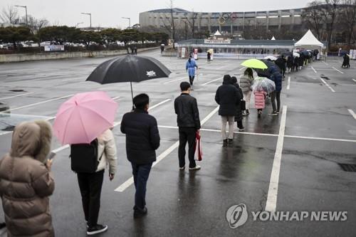 People wait in line to get tested for COVID-19 at a makeshift testing booth set up at a parking lot of the Jamsil Olympic Stadium in Seoul's eastern district of Songpa on Jan. 25, 2022. (Yonhap)