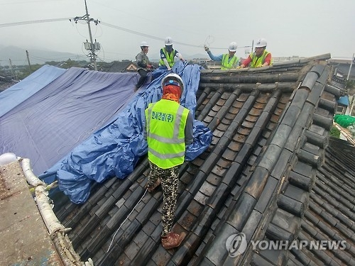 (경주=연합뉴스) 김준범 기자 = 경북도와 경주시·군, 민간단체 등이 16일 오전 지진피해를 본 경북 경주시 황남동 주택 기와에 천막을 덮고 있다. 2016.9.16psykims@yna.co.kr
