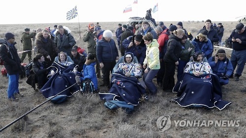 (EPA=연합뉴스) 미국 여성 우주인 캐슬린 루빈스(왼쪽), 러시아 우주인 아나톨리 이바니쉰(가운데), 일본 우주인 오니시 다쿠야 등이 30일(현지시간) 소유스 우주선 귀환캡슐을 이용해 카자흐스탄 초원 지대에 내린 뒤 안정을 취하고 있다.