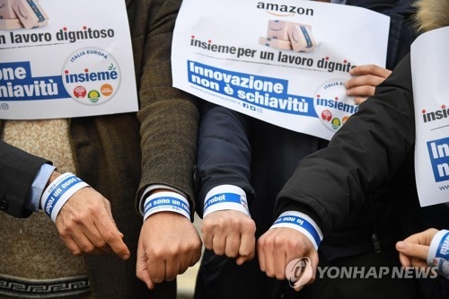 업무 효율을 위해 개발된 아마존의 전자 팔찌에 항의하며 2일 로마에서 플래시 몹을 펼치고 있는 이탈리아 노동 활동가들. 이들은 "혁신은 노예가 아니다"라는 문구가 담긴 홍보물을 들고 시위를 벌였다. [EPA=연합뉴스] 