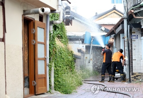 쪽방촌 열기를 낮춰라(대구=연합뉴스) 김준범 기자 = 대구시소방안전본부 관계자들이 3일 오후 중구 한 쪽방촌의 무더위 피해를 줄이기 위해 골목길에 물을 뿌리고 있다. 2018.8.3