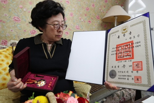 어머니에게 추서된 훈장 바라보는 작은딸