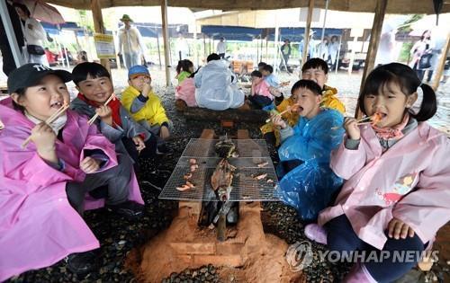 와일드푸드축제장서 직접 잡은 물고기 구워 먹는 어린이들