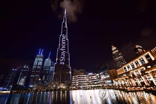 24일 아랍에미리트(UAE) 두바이의 세계 최고 빌딩 부르즈 칼리파의 외벽에 '집에 머물자'라는 문구가 밝혀졌다. [AFP=연합뉴스]