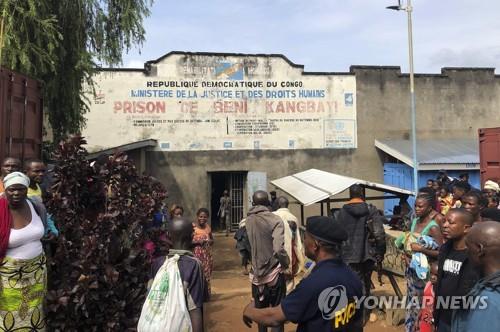 20일 집단 탈주가 일어난 캉바이 교도소의 깨진 문을 콩고 주민들이 쳐다보고 있다.