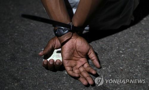 한 남성이 지난 9일 남아공 프리토리아에서 야간통금 위반혐의로 체포돼 앉아있다.