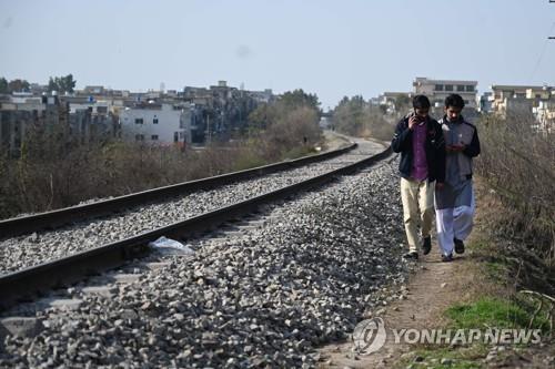 파키스탄 라왈핀디의 철로 변에서 휴대전화로 통화하며 걷고 있는 남성. [AFP=연합뉴스]