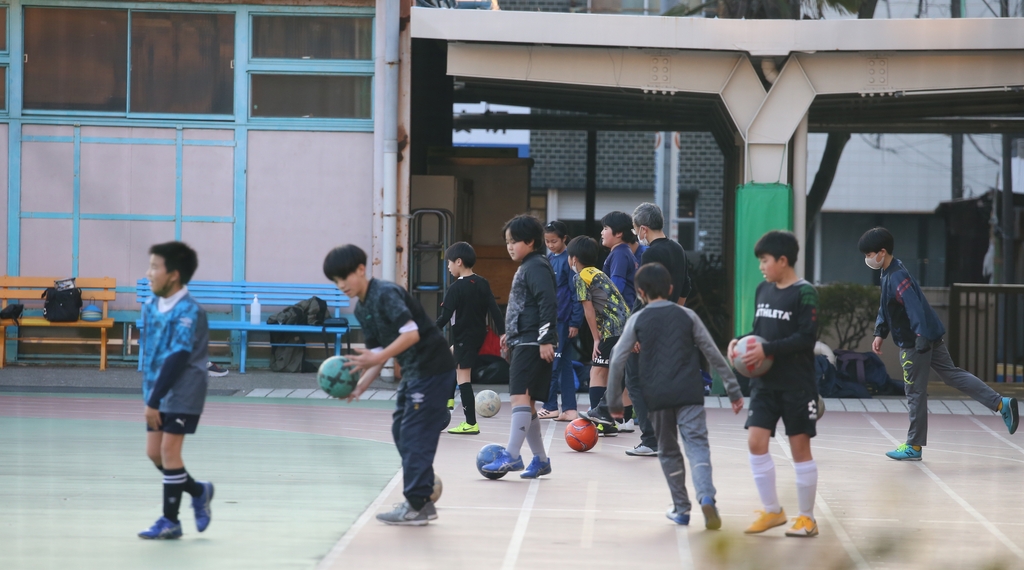 토요일 오후 도쿄의 한 공립 초등학교에서 학생들이 방과 후 체육활동을 하고 있다. 방과 후 활동 지도자로 보이는 어른이 학생들 사이에서 함께 움직이고 있다. 촬영 이세원