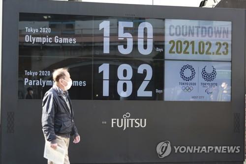 (도쿄 AP=연합뉴스) 일본 도쿄 시내에서 23일 한 행인이 하계 올림픽 개최가 150일 앞으로 다가왔음을 알리는 전광판 주변을 지나가고 있다. jsmoon@yna.co.kr
