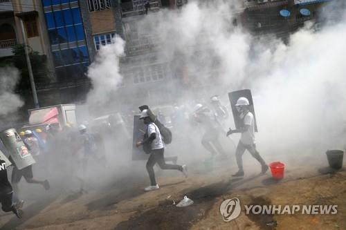양곤에서 군경이 발포한 최루탄 사이를 뛰어가는 시위대