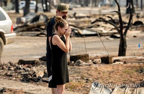 한 여성이 4일(현지시간) 미 캘리포니아 그린빌에서 발생한 딕시 화재로 잿더미가 된 어머니의 집을 보면서 울고 있다. 이 화재로 그린빌 마을 대부분이 파괴됐다. [AFP=연합뉴스]