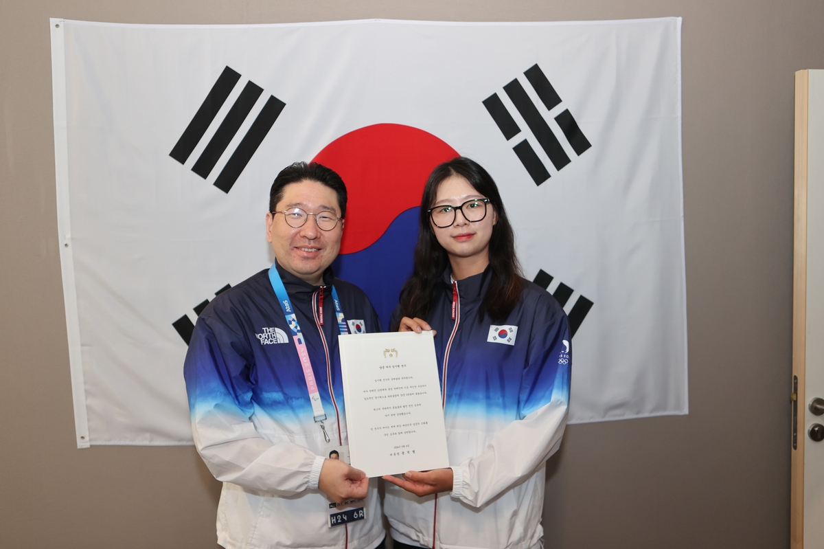 양궁 3관왕 임시현 선수와 함께 대통령 축전을 들어 보이는 이상현 회장(왼쪽)