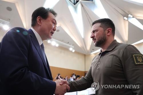 El presidente surcoreano, Yoon Suk Yeol (izda.), estrecha la mano de su homólogo ucraniano, Volodímir Zelenski, durante una sesión ampliada de la cumbre del Grupo de los 7 (G-7), celebrada, el 21 de mayo de 2023, en Hiroshima, Japón. (Foto del cuerpo de prensa. Prohibida su reventa y archivo)