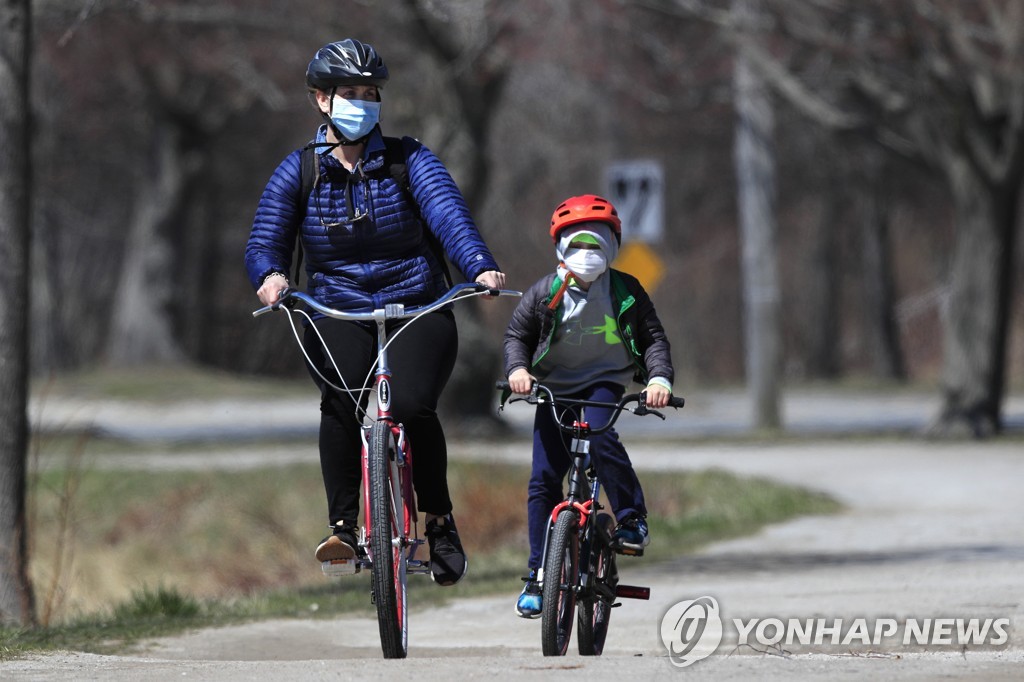 미국 메인주 포틀랜드에서 마스크를 착용하고 자전거를 타는 가족