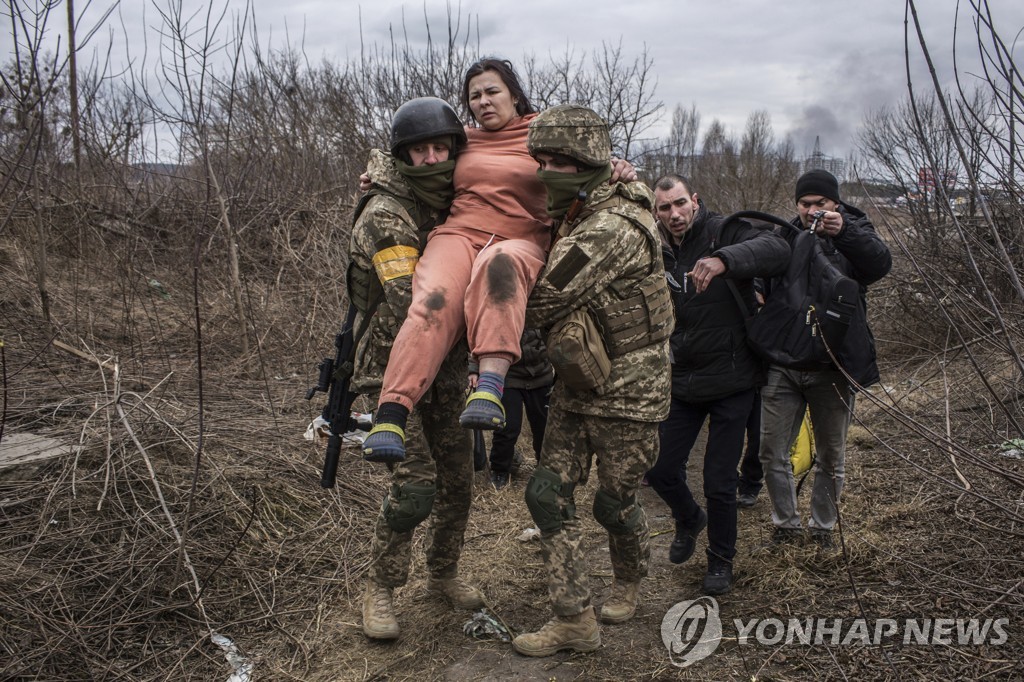 2022년 3월 6일 우크라이나 수도 키이우 인근 소도시 이르핀에서 우크라이나군 장병들이 강을 넘어 피난하려는 주민을 돕고 있다. [AP 연합뉴스, 재판매 및 DB 금지]