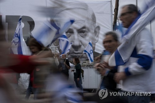 사법정비 입법에 반대하는 시위대가 베냐민 네타냐후 총리 초상화가 내걸린 텔아비브 거리를 지나고 있다.
