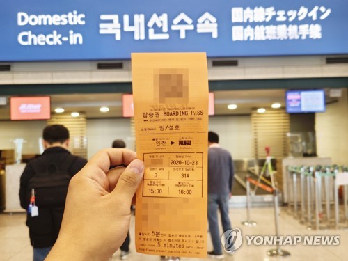 A customer holds up a Jeju Air Co.'s boarding ticket at Incheon International Airport, west of Seoul, on Oct. 23, 2020, for a special one-hour flight that departs from Incheon and returns to the airport as the carrier strives to survive the coronavirus crisis. (Yonhap)