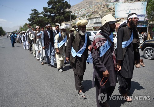 지난달 12일 아프가니스탄 남부 헬만드 주에서 출발한 평화협상 요구 행진 참가자들인 18일 목적지인 수도 카불에 도착해 걷고 있다.[AFP=연합뉴스]