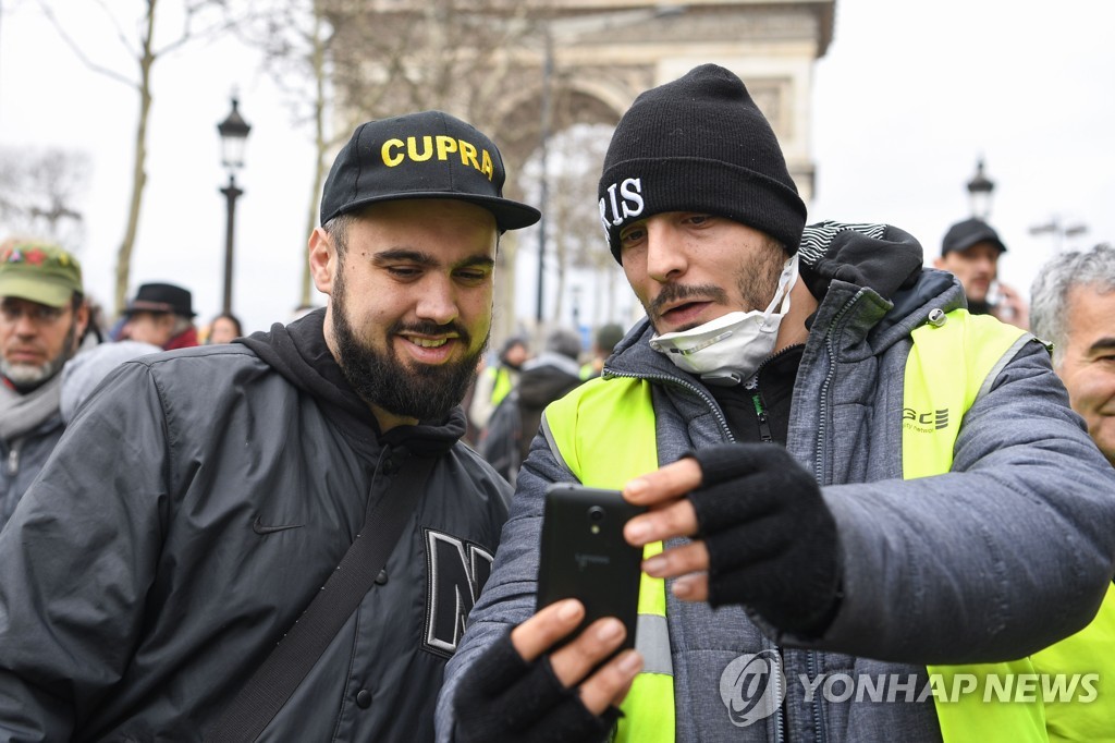 지난 2일 파리 개선문 앞 '노란 조끼' 시위에서 시위에 참여한 한 시민이 에릭 드루에(왼쪽)와 함께 사진을 찍고 있다. [AFP=연합뉴스]