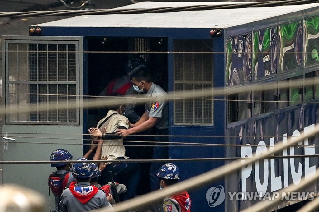 지난 27일 미얀마 양곤에서 한 경찰이 시위 참가자를 체포하고 있다.