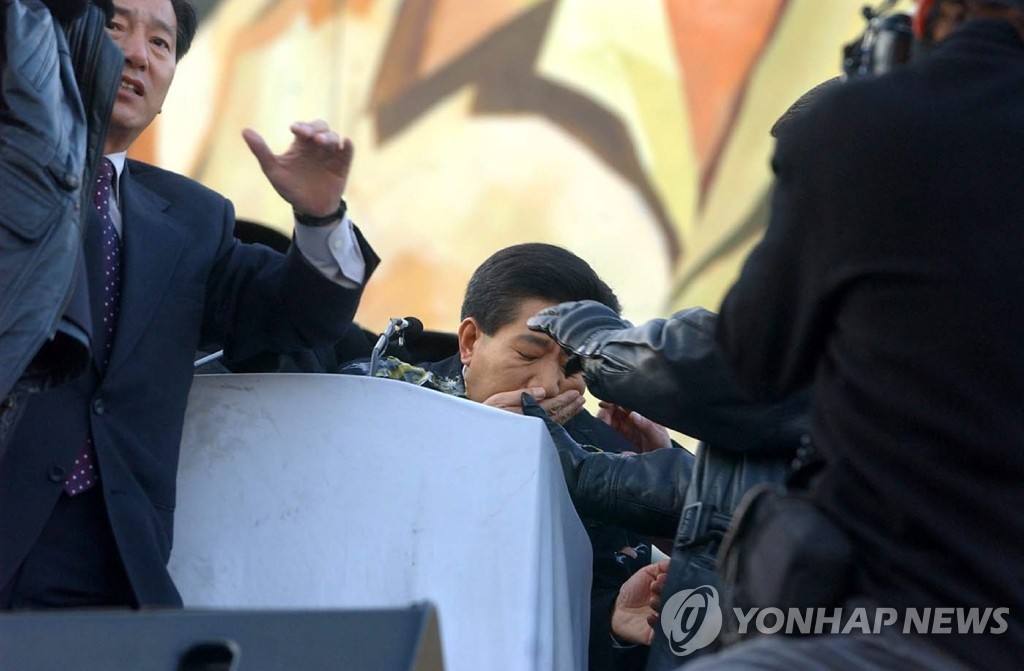 2002년 11월 13일 오후 서울 여의도 한강 둔치에서 열린 농민대회에 참석, 연설을 하던 민주단 노무현 후보가 농민이 던진 달걀을 맞고 입을 감싸고 있다. [연합뉴스 자료사진]