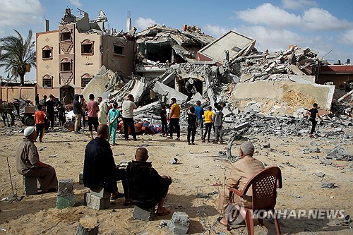 이스라엘의 공습으로 무너진 건물 더미를 지켜보는 가자지구 주민들