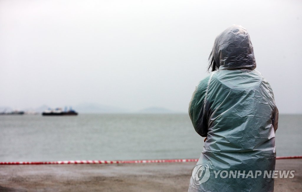 <세월호참사> 야속한 날씨세월호 침몰 12일째인 27일 오전 전남 진도군 팽목항에서 우비를 입은 한 실종자 가족이 바다를 바라보고 있다. 2014.4.27