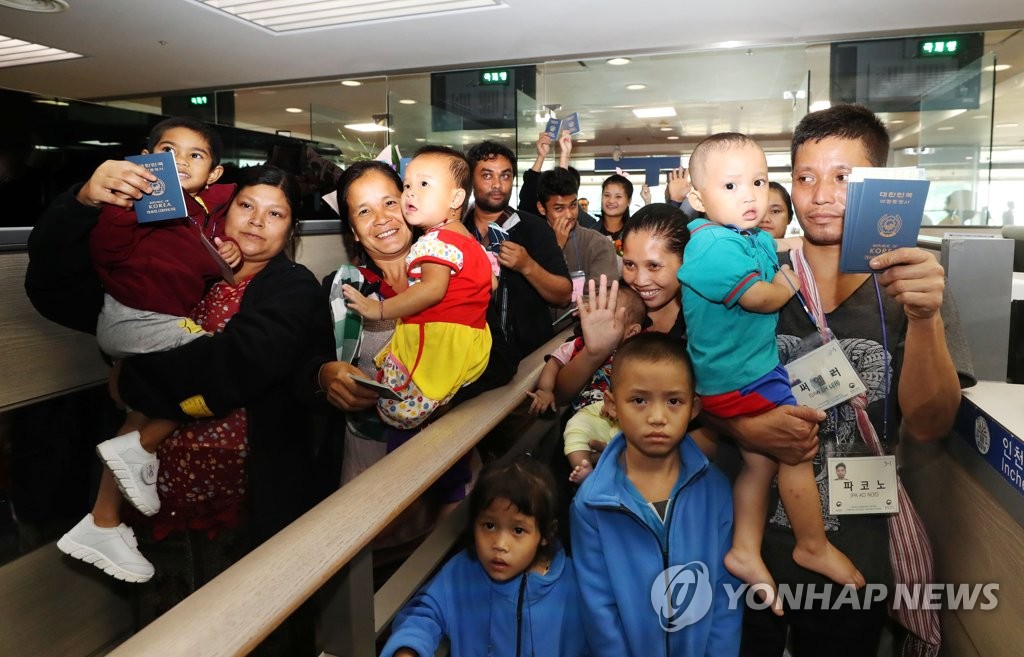 仁川空港の入国審査場でパスポートを掲げる難民の家族＝２５日、仁川（聯合ニュース）