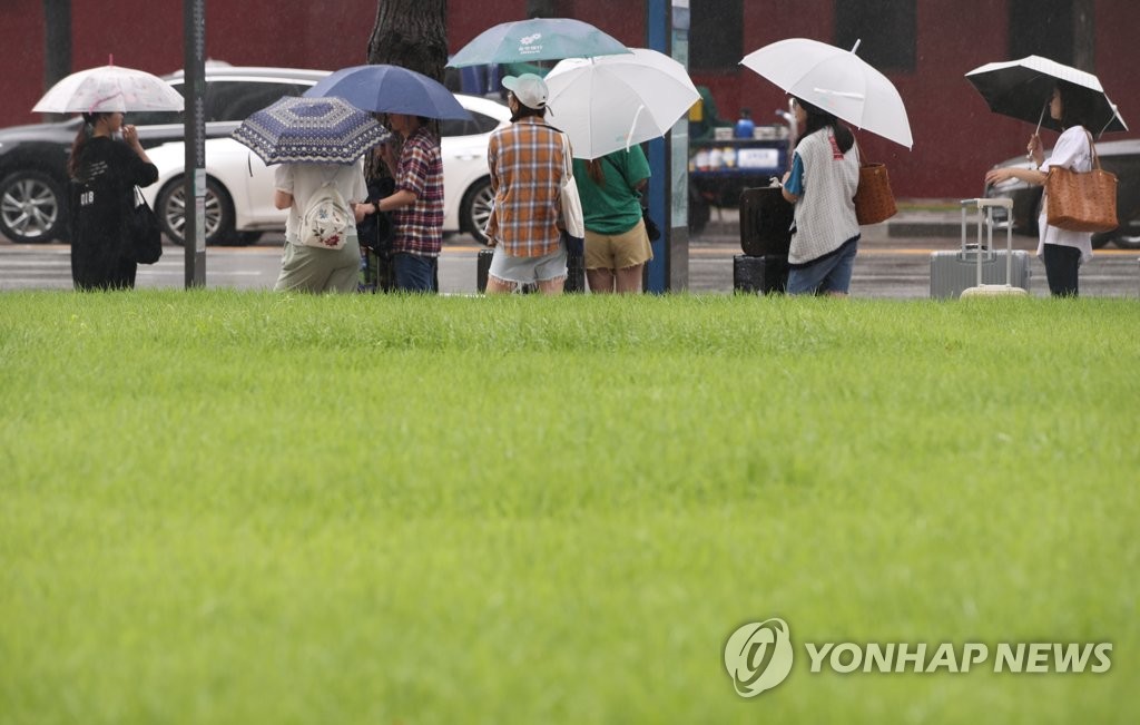 우산을 쓴 시민과 관광객들이 버스를 기다리고 있다. [연합뉴스 자료사진]