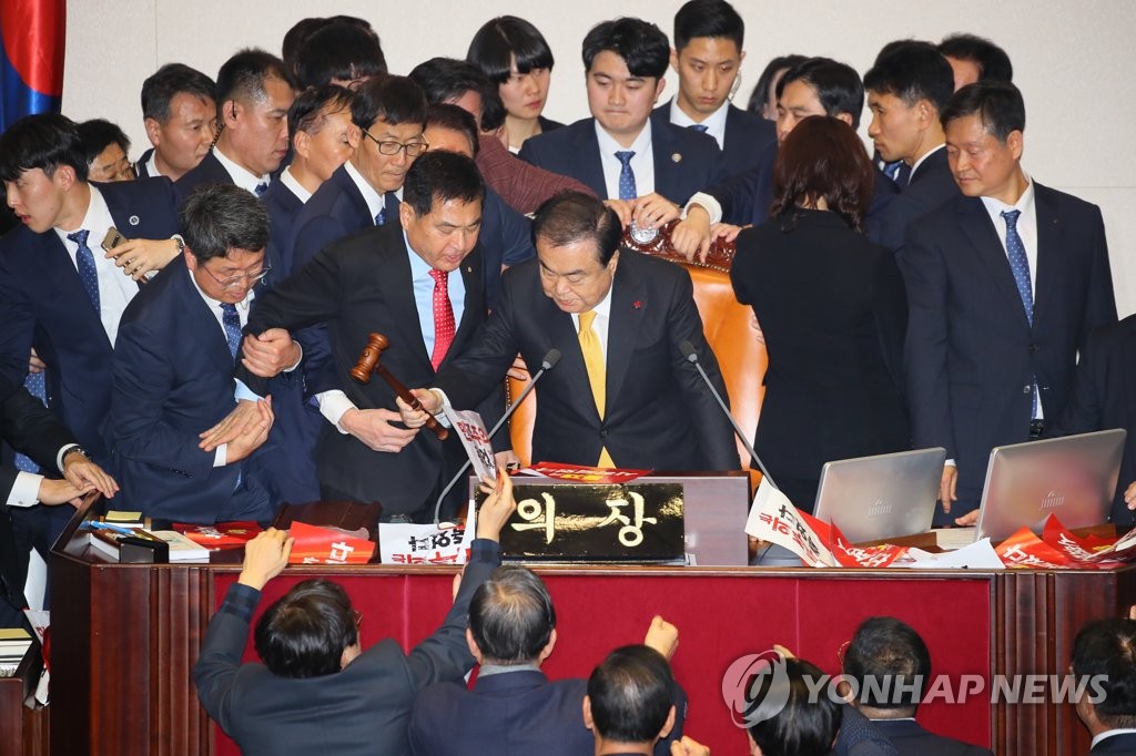National Assembly Speaker Moon Hee-sang (C) bangs the gavel to announce the passage of an electoral reform bill amid protests by Liberty Korea Party lawmakers at the National Assembly on Dec. 27, 2019. (Yonhap)