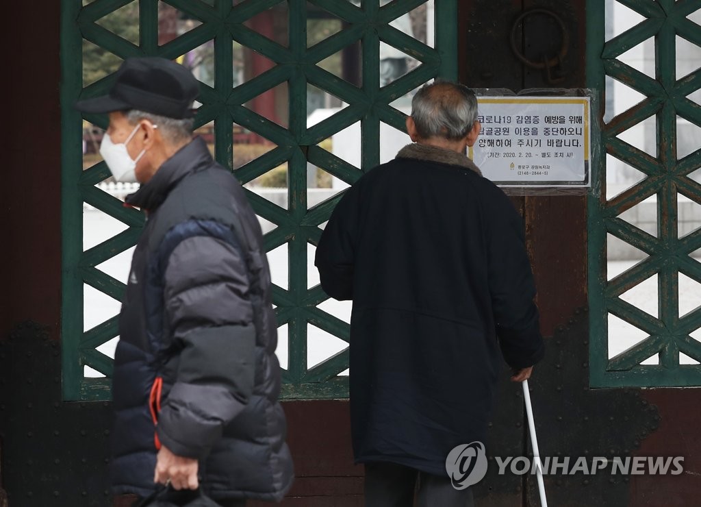 Visitors stand in front of a gate at Tapgol Park in central Seoul Feb. 21, 2020. The park, popular among the city's senior citizens, was closed down following the coronavirus outbreak in the capital. (Yonhap)