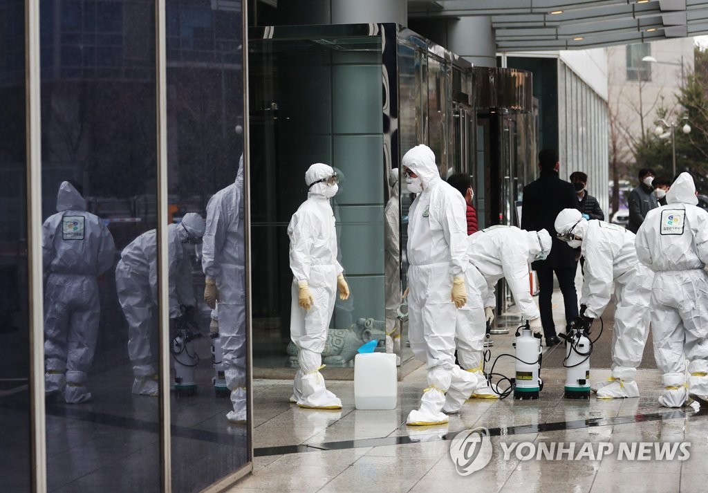 Workers clad in protective gear sort out equipment for disinfection at the LS Yongsan Tower in Seoul on Feb. 25, 2020. They disinfected the closed high-rise after a worker there was found to be infected with the new coronavirus the previous day. (Yonhap)