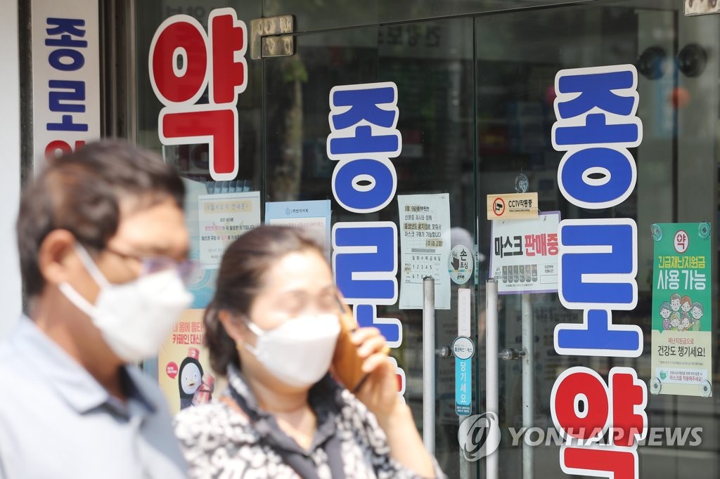 Pedestrians wearing face mask walk past a pharmacy in the central Seoul ward of Jongno on May 31, 2020. (Yonhap)