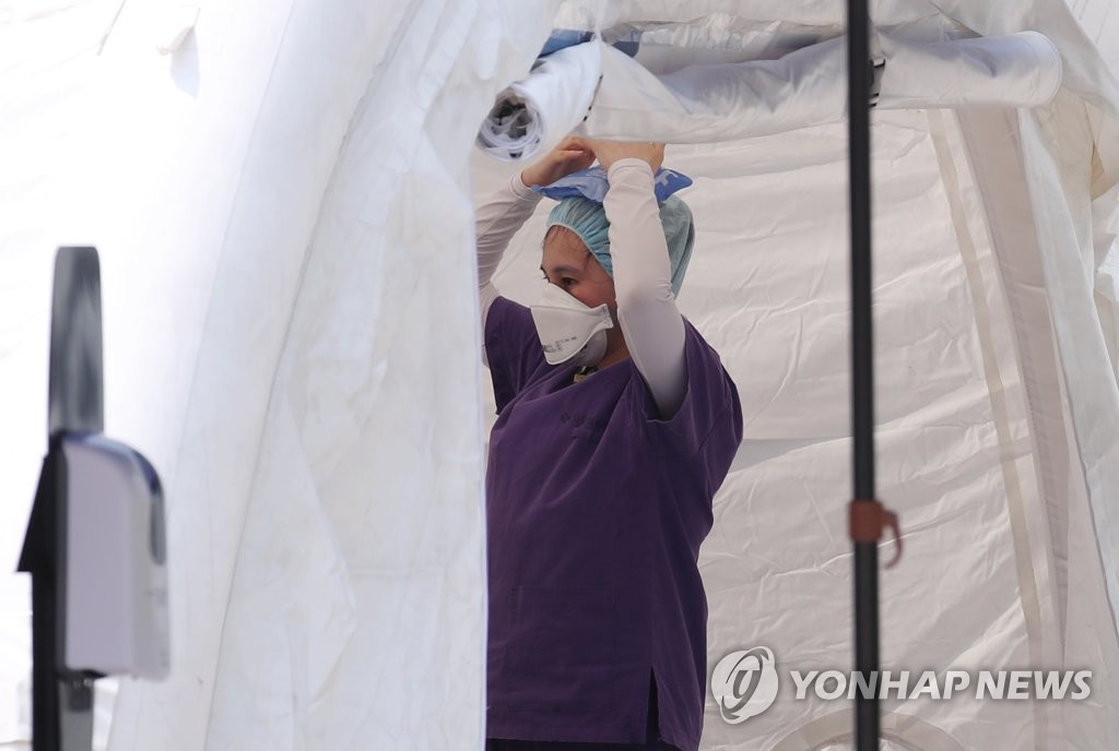 A medical worker cools her head with an ice pack at a makeshift clinic in northern Seoul on June 8, 2020. (Yonhap)