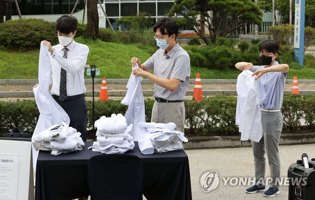 Trainee doctors at Seoul National University Hospital in Seoul take off their white gowns on Aug. 23, 2020, in a protest of the government's plan to increase medical school admission quotas. (Yonhap)