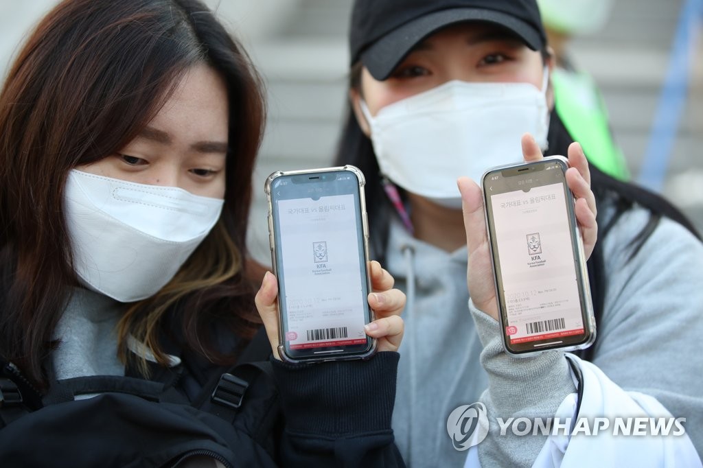 Fans hold up mobile tickets before entering a soccer event in Goyang, north of Seoul, on Oct. 12, 2020. (Yonhap)