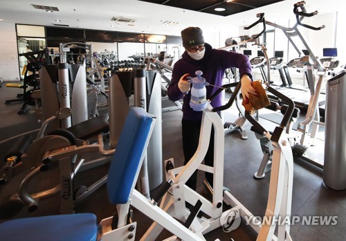 An employee at a gym in Yongin, south of Seoul, disinfects fitness equipment on Jan. 17, 2021, to prepare for opening as the government eases restrictions on indoor sports facilities. (Yonhap)